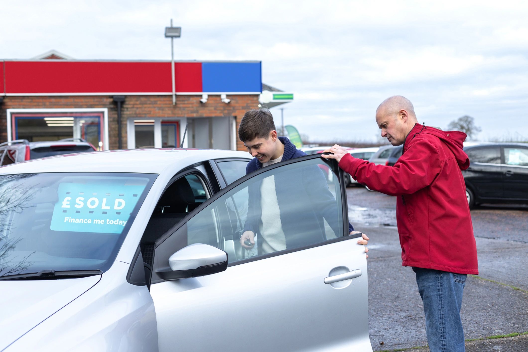 Happy car buyer receiving keys at dealership